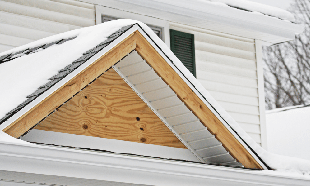 kivitelezés: egy háromszög alakú tetődíszítés közelről, a háttérben a ház második emeletével, enyhén havas környezetben