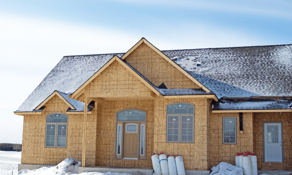 kivitelezés: egy földszintes, modernebb stílúsú ház fa alapja kintről, enyhén havas környezetben